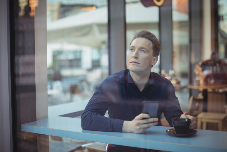 Person sits by a window with coffee, staring off as if experiencing déjà vu.