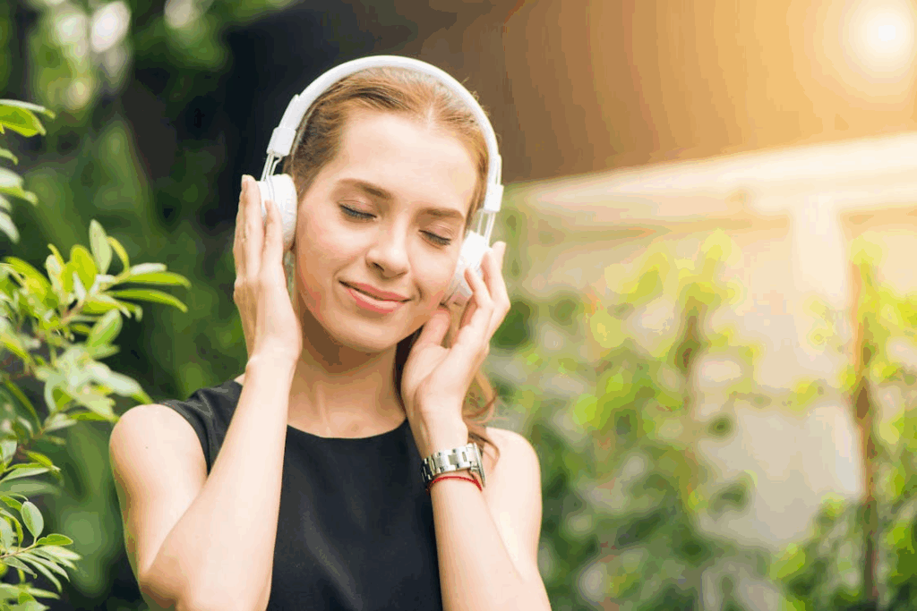Woman wearing headphones outdoors, experiencing frisson and showing why sounds give you chills.