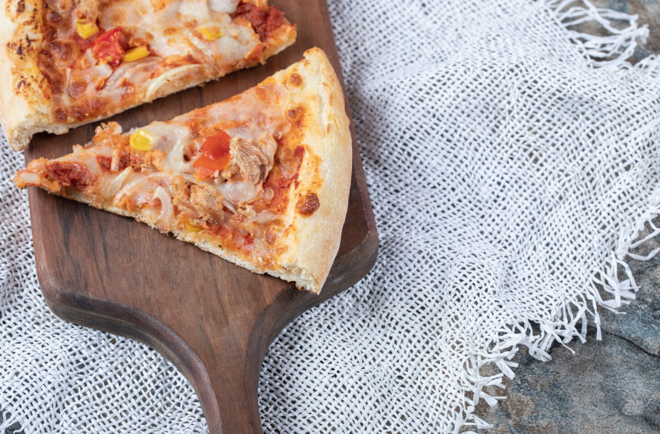 Two slices of leftover pizza on a wooden board
