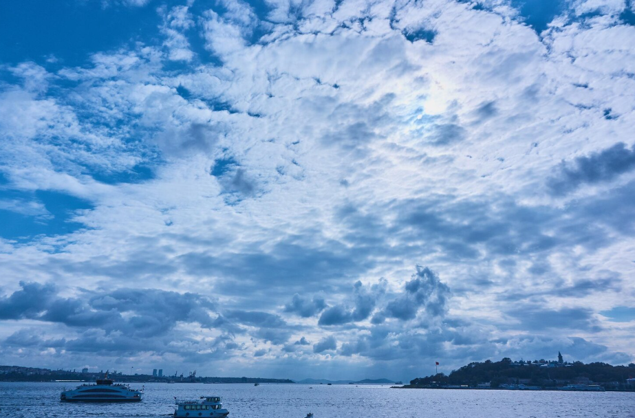 Blue sky with scattered clouds over a bay, illustrating why the sky looks blue