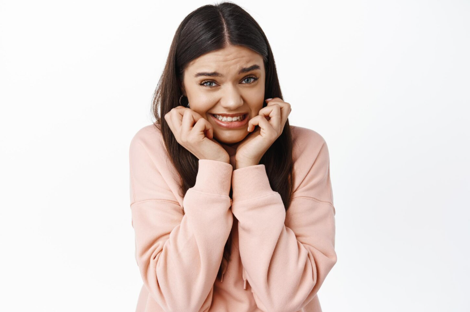 Nervous young woman embarrassed with her hands in face.