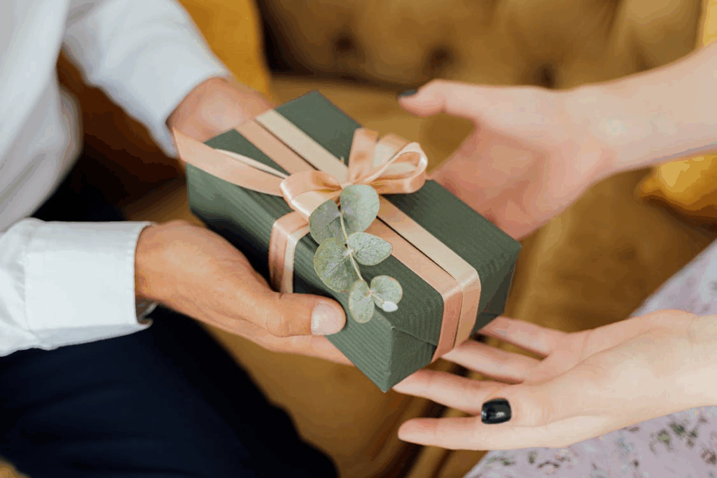 Hands exchanging a wrapped green gift, showing the psychology of giving and connection.