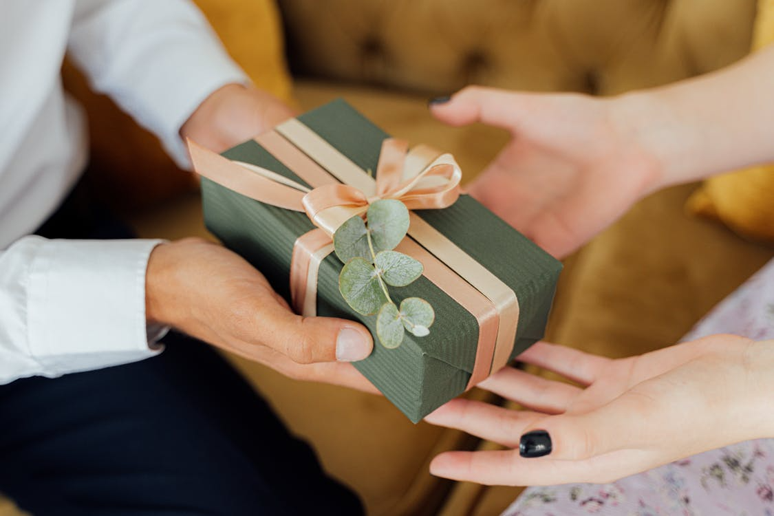 Hands exchanging a wrapped green gift, showing the psychology of giving and connection.