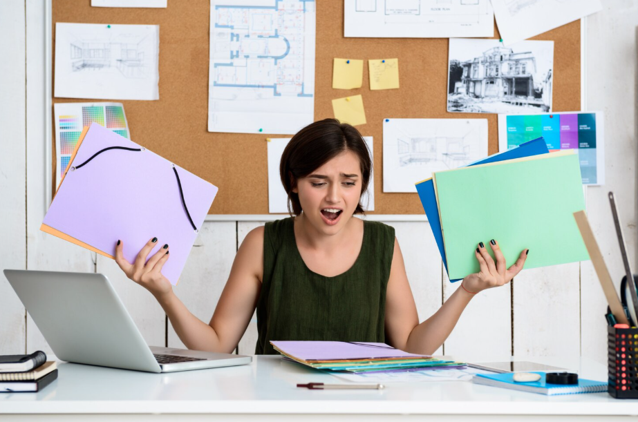 Juggling folders at a cluttered desk, illustrating task switching costs and lost focus.